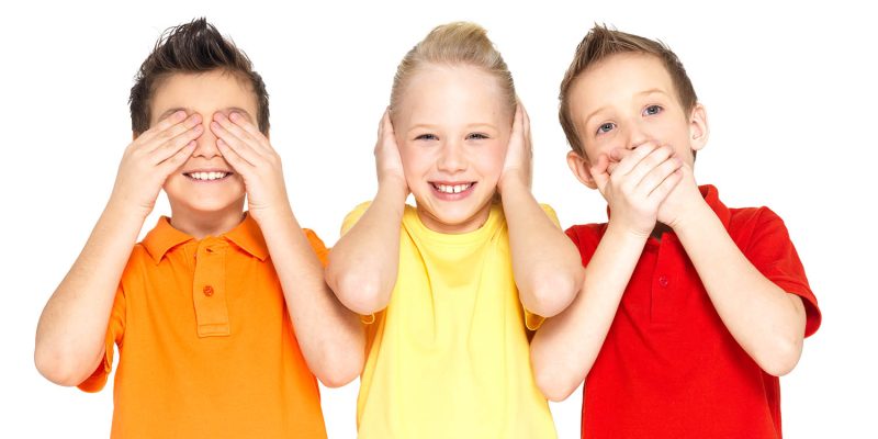 Funny faces of happy children doing "See Nothing, Hear Nothing, Say Nothing..." isolated on white background